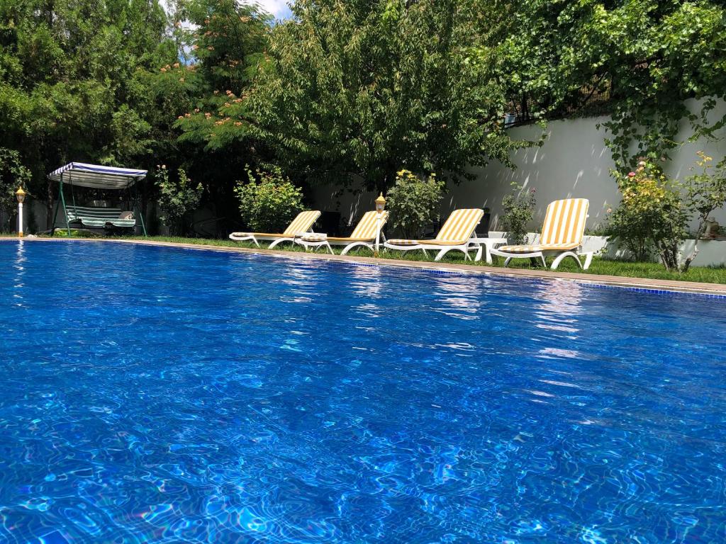 a swimming pool with three chairs sitting next to it at GARDEN OTEL AMASYA in Amasya
