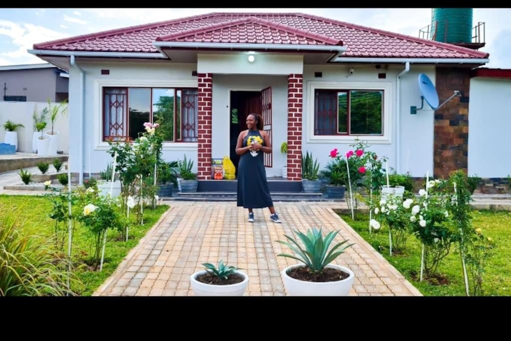 Una donna in piedi davanti a una casa di Banjii's Cottage a Lusaka