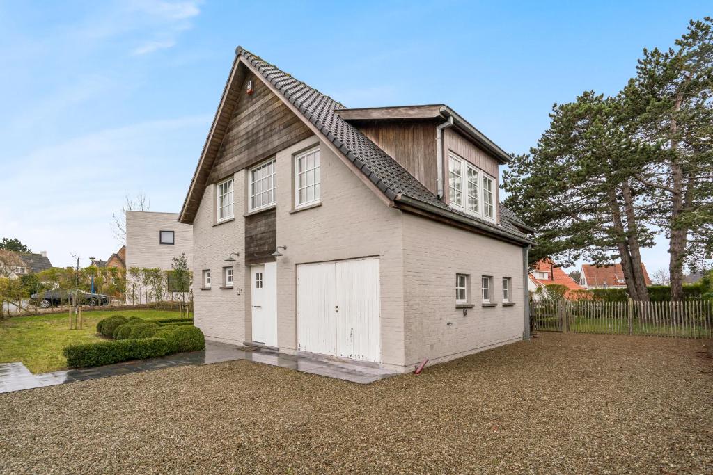 una gran casa blanca con garaje en Luxe familievilla voor 9pers met zee en tuinzicht, en Koksijde