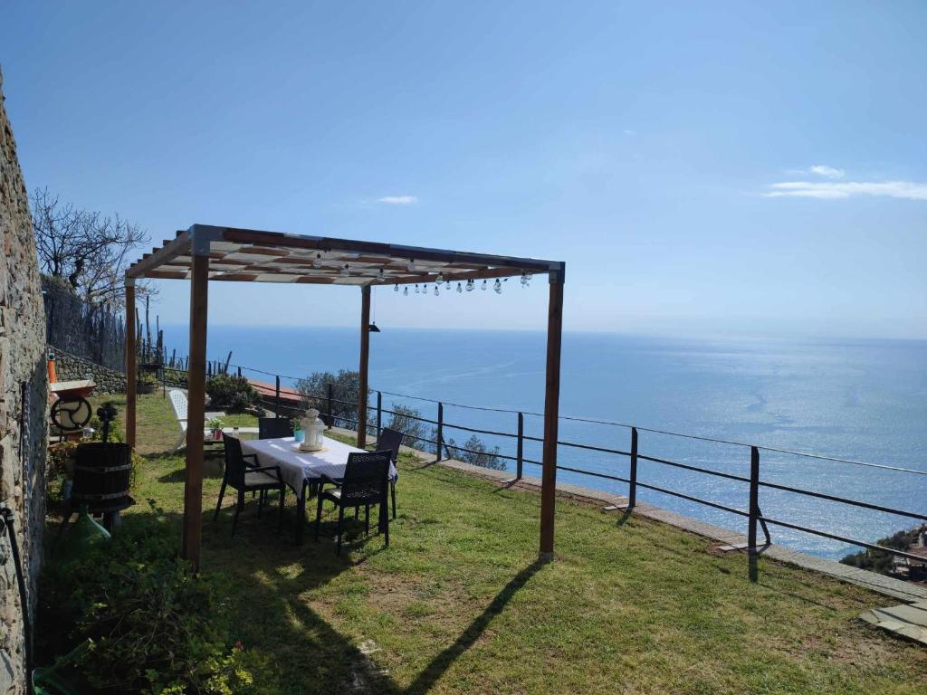 een tafel en stoelen onder een pergola met uitzicht op de oceaan bij Casa a picco sul mare 5 terre in Campiglia