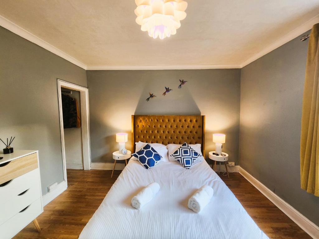 - une chambre avec un grand lit blanc et des oreillers bleus dans l'établissement House near restaurants, park and pubs, perfect for pets!, à Bristol