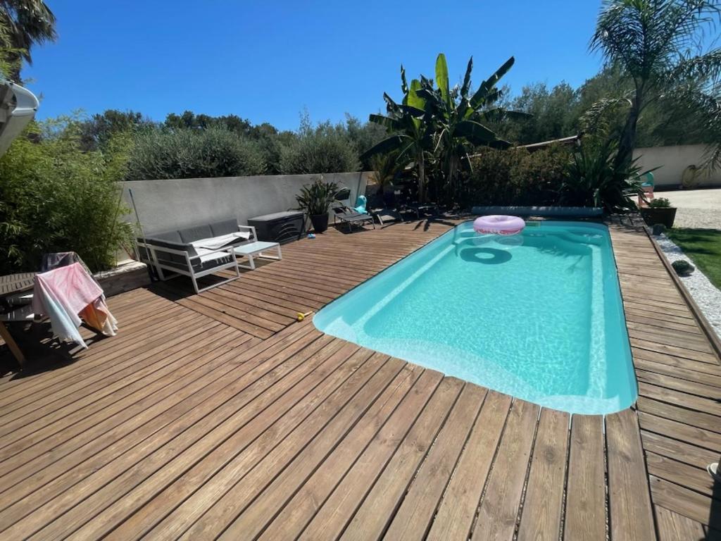 une terrasse en bois avec une piscine au-dessus d'une terrasse en bois dans l'établissement Madinina, à Bormes-les-Mimosas