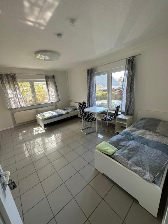Schlafzimmer mit einem Bett, einem Tisch und Fenstern in der Unterkunft Gästezimmer - Elbert in Hösbach