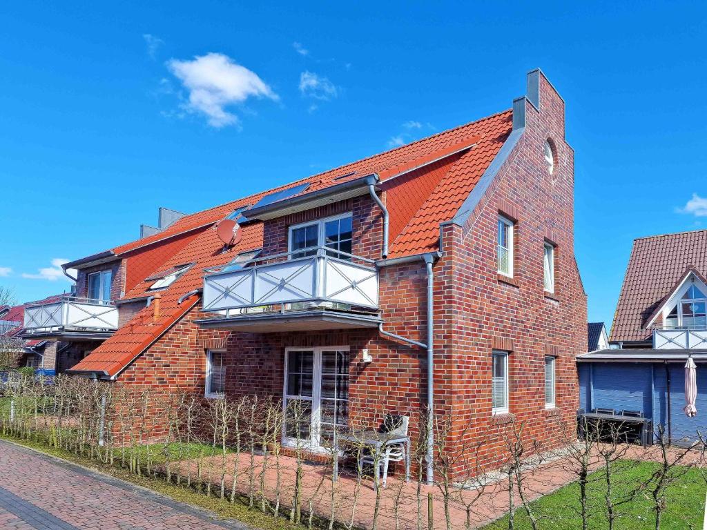 a red brick house with a balcony on a street at Herings Kajüte in Greetsiel
