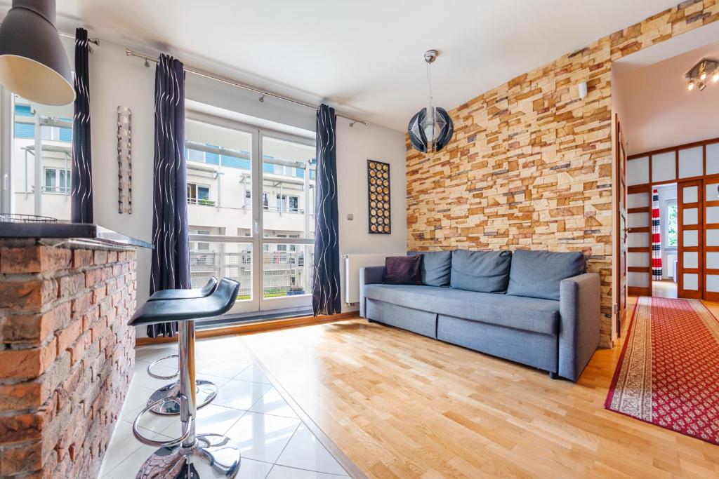 a living room with a blue couch and a brick wall at Apartamenty Sun & Snow Maria Ludwika in Sopot