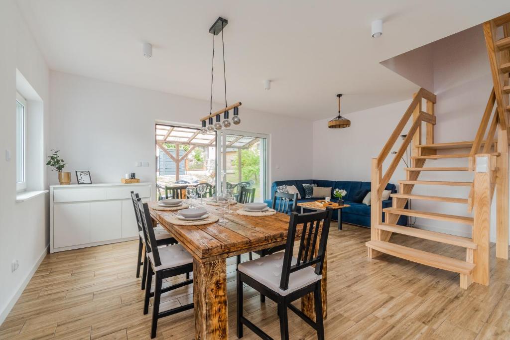 a kitchen and dining room with a wooden table and chairs at Flatbook Apartamenty - Sztutowo Dom Morska in Sztutowo