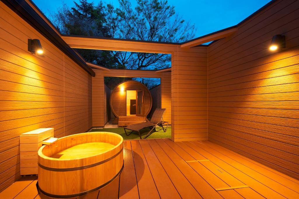 a sauna with a tub on a wooden deck at Meitei no Yado Hotel Koshien in Fuefuki