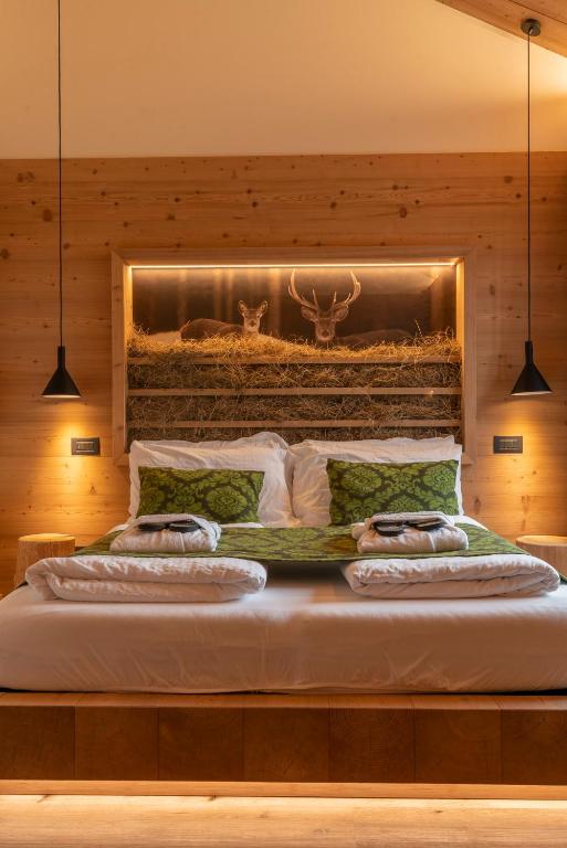 a bedroom with a large bed with two antlers on the wall at Casera Pian Grand Wellness Lodge in Chies dʼAlpago