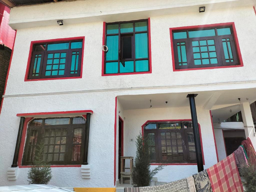 biały budynek z czerwonymi i niebieskimi oknami w obiekcie Sea Green Guest House w mieście Śrinagar