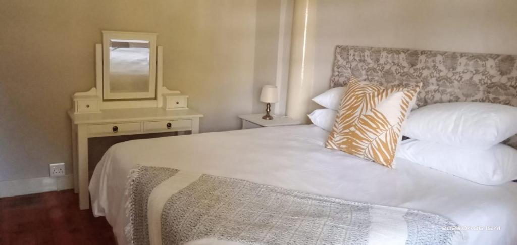 sypialnia z dużym białym łóżkiem z lustrem w obiekcie Capital On French Guest House w mieście Pietermaritzburg