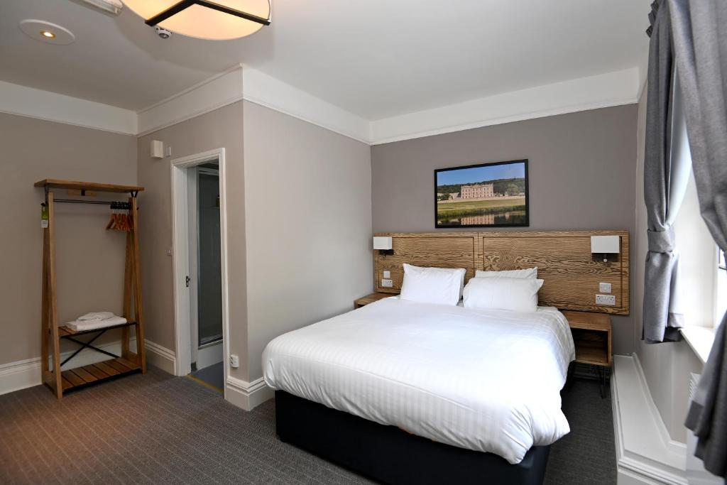 a bedroom with a large bed with white sheets at Wheatsheaf, Baslow by Marston's Inns in Baslow