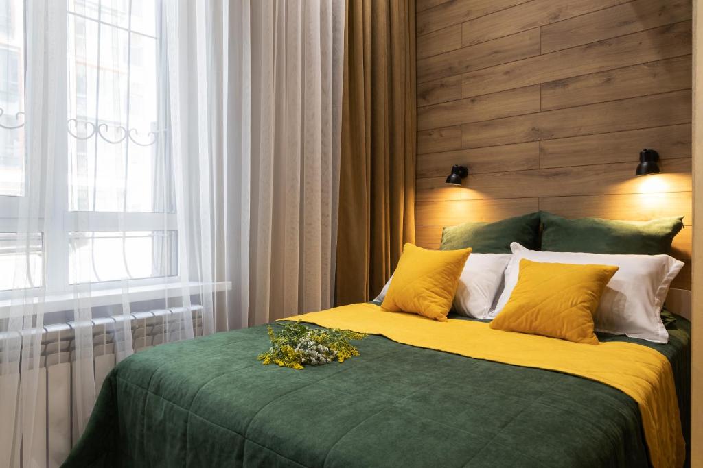 a bedroom with a bed with a green blanket and yellow pillows at Апартаменты Comfort Life 92 in Almaty