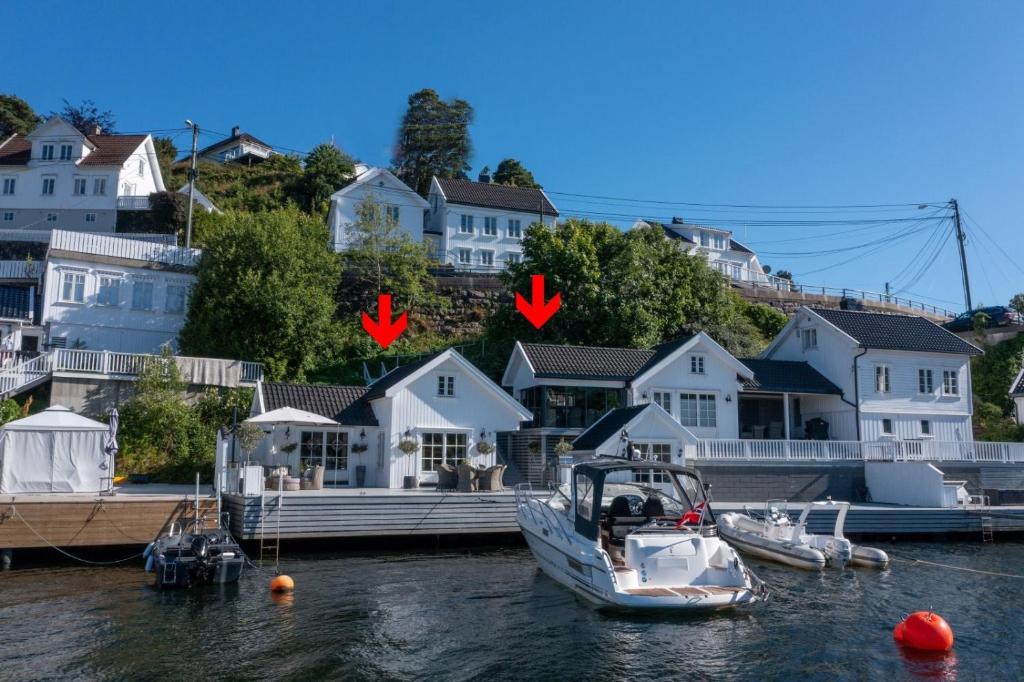 dwie łodzie są zacumowane w doku z domami w obiekcie Båthus med egen stor brygge og alle fasiliteter w mieście Arendal
