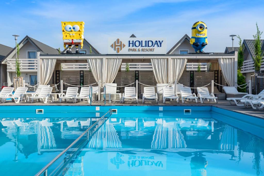 a pool at a hotel with chairs and a hotel sign at Holiday Park & Resort Grzybowo in Grzybowo