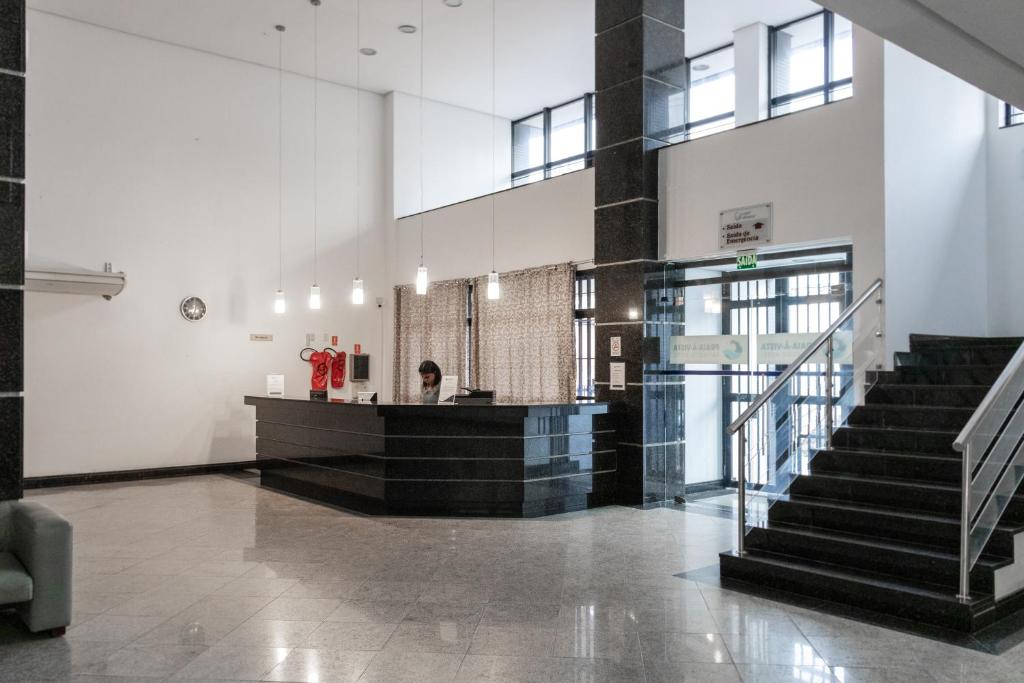 a lobby with stairs and a counter in a building at Praia a Vista Salvador Hotel in Salvador