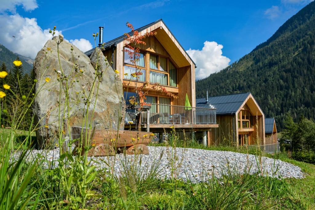 a house in the mountains with a large rock at HOCHoben Chalets & Mobilhomes in Mallnitz