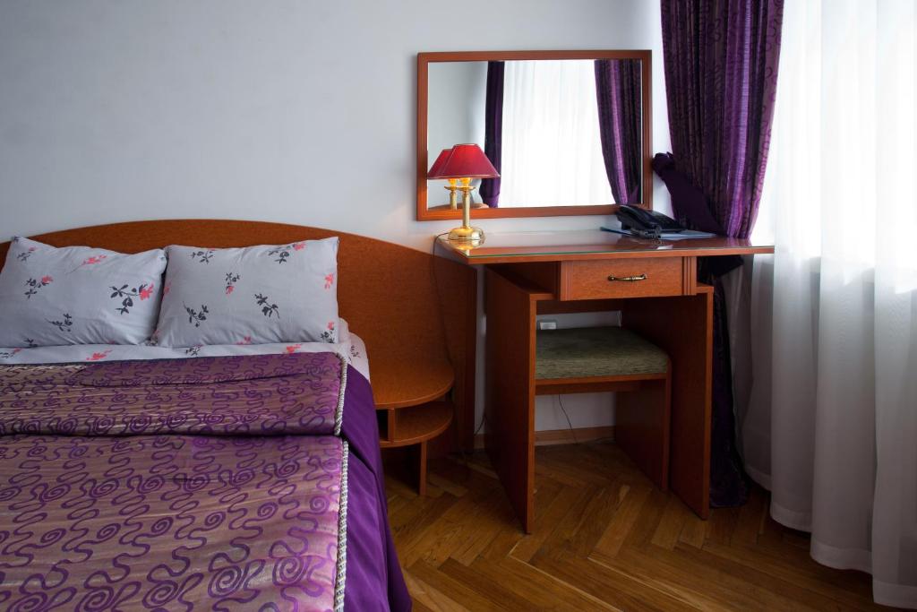 a bedroom with a bed and a desk with a mirror at Hetman Hotel in Lviv