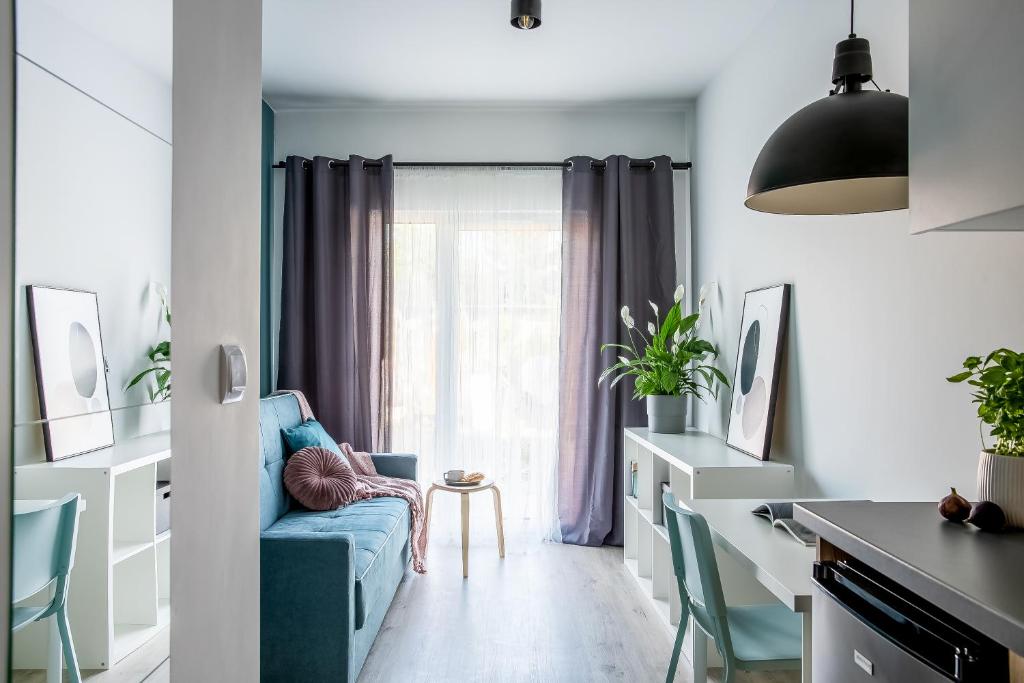 un soggiorno con divano blu di fronte a una finestra di ADLER Apartments --prywatny taras przy pokoju, dostęp na kod -- BEZPŁATNY PARKING a Łódź