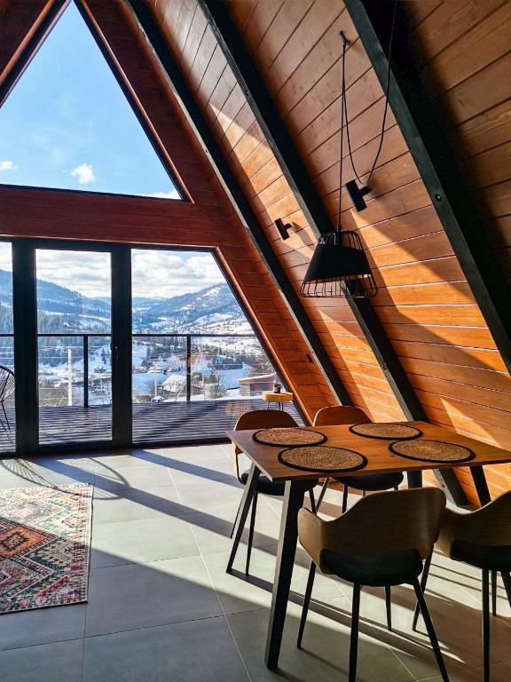 a room with a table and chairs and a large window at Mirador Cottage in Slavske