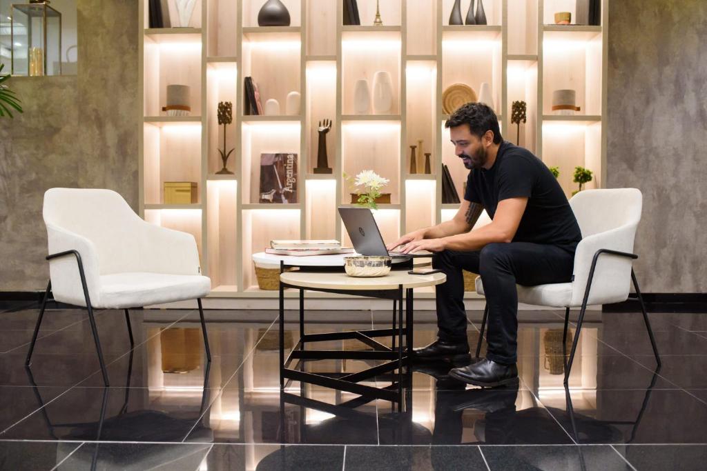 un homme assis sur une chaise devant un ordinateur portable dans l'établissement 1253 Recoleta Small Hotel, à Buenos Aires