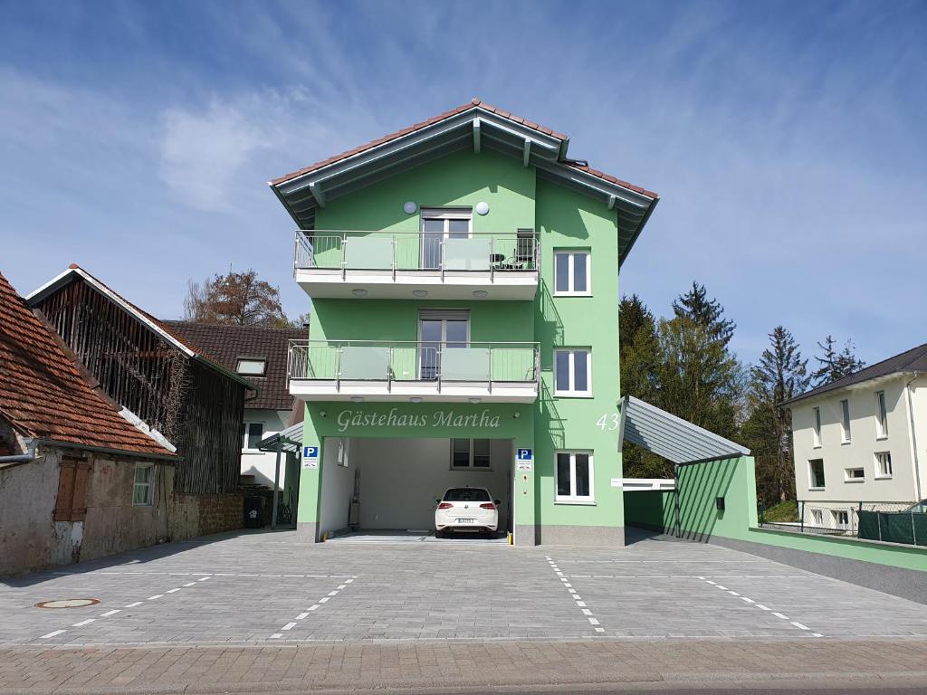 ein grünes Gebäude mit einem Auto auf einem Parkplatz in der Unterkunft Gästehaus Martha in Rust