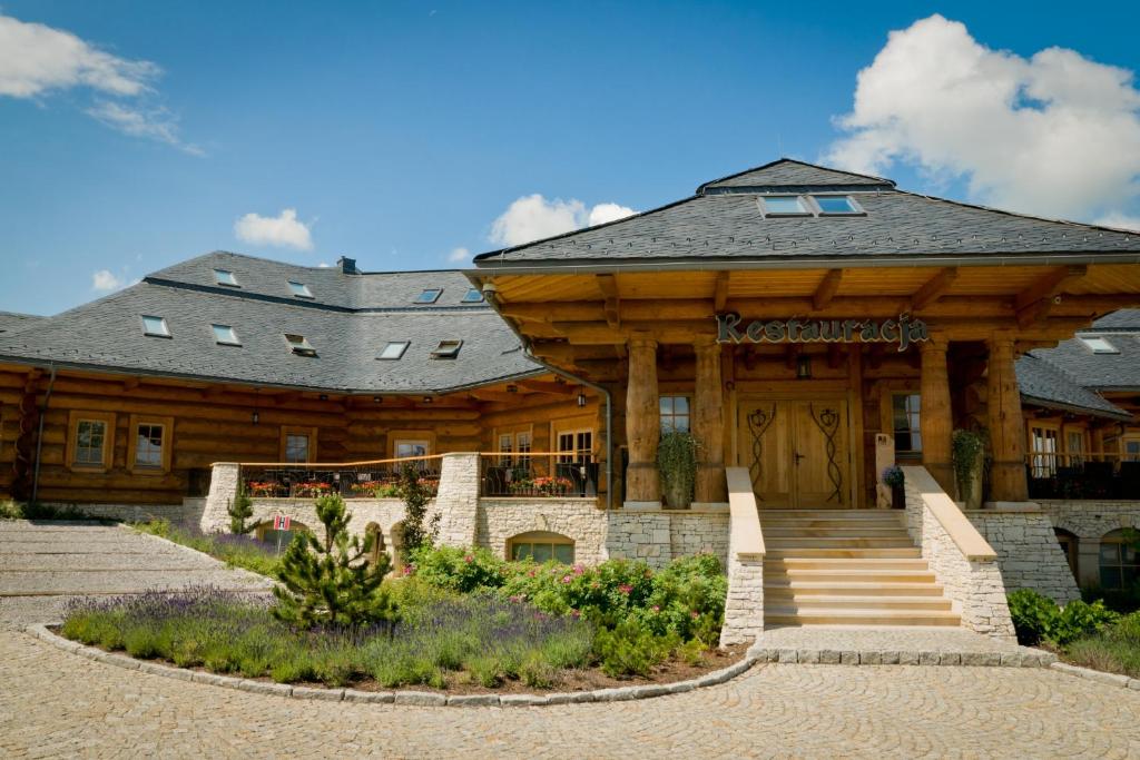 a large log building with the front of it at Chochołowy Dwór in Jerzmanowice