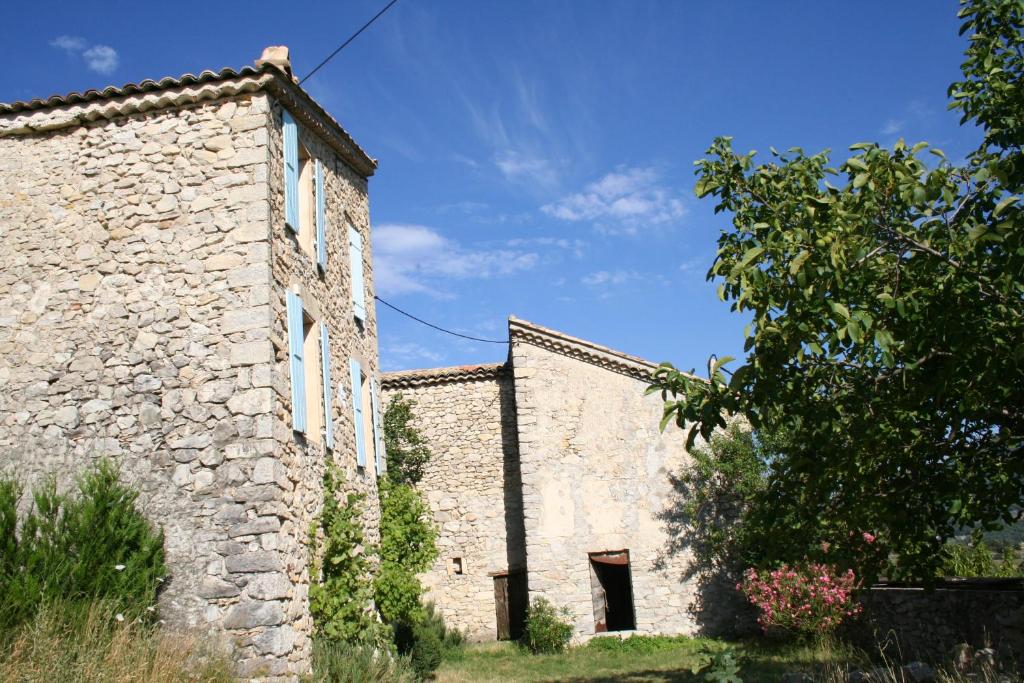 an old stone building with a tree next to it at Meublé en Drôme Provençale in Saint-Auban-sur-Ouvèze
