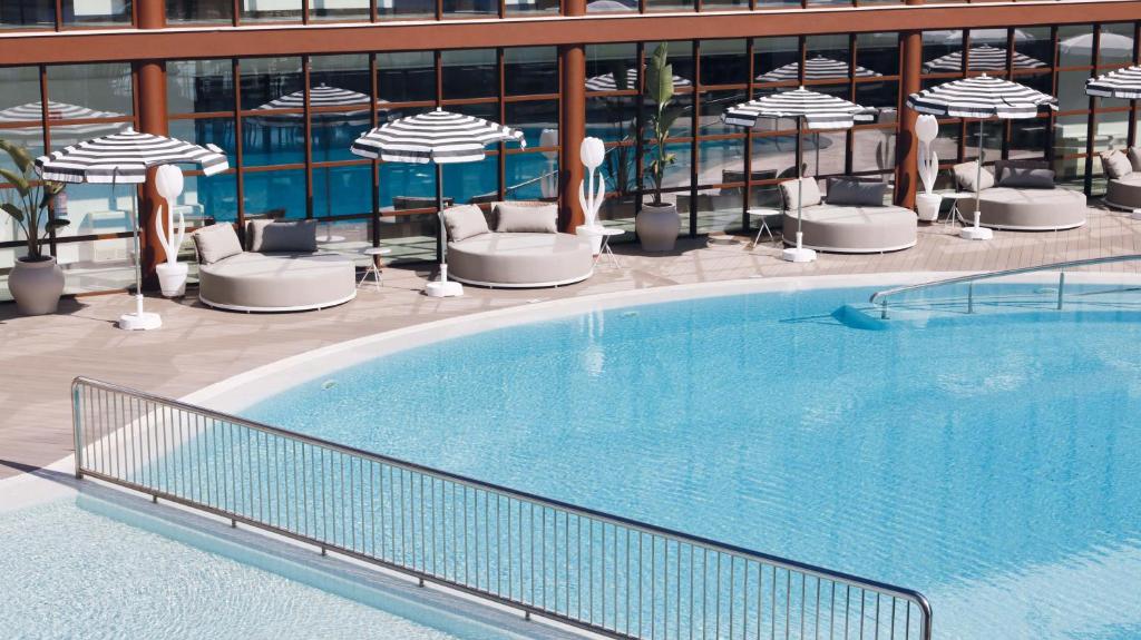 una gran piscina con sillas y sombrillas en Seth Port Ciutadella en Ciutadella
