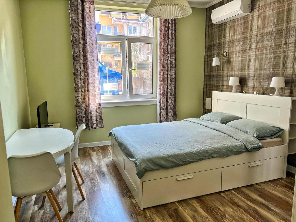 a bedroom with a bed and a table and a window at Студио Top City Center in Plovdiv