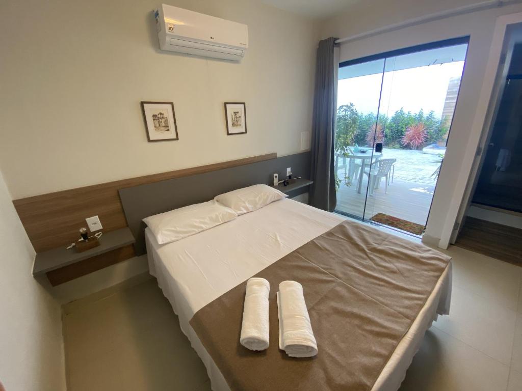 a bedroom with a bed with white sheets and a window at Vila das Dunas - aluguel de temporada in Cabo Frio