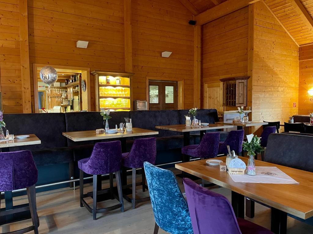 una sala da pranzo con tavoli e sedie viola di Kitz Alm Saarwellingen a Saarwellingen