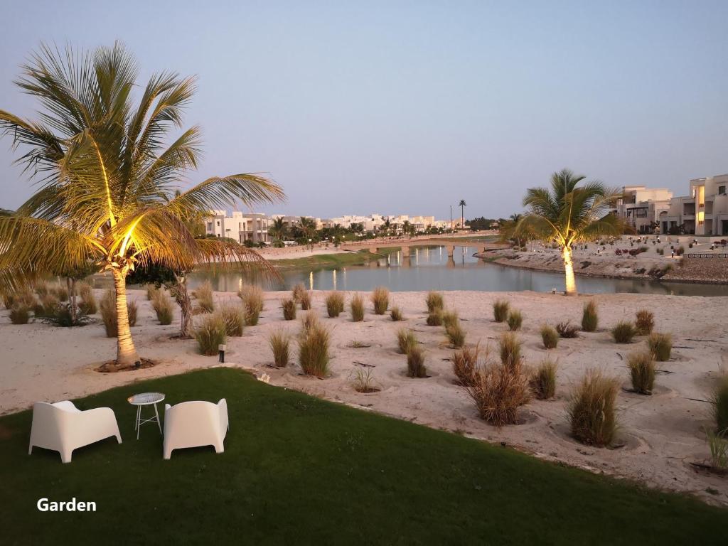 a beach with two chairs and a table and palm trees at Laguna Apartment HAWANA SALALAH Resort in Salalah