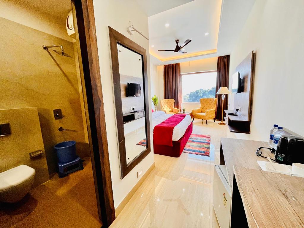 Habitación de hotel con baño y dormitorio en Ganges blossam - A Four Star Luxury Hotel & Resort en Haridwār