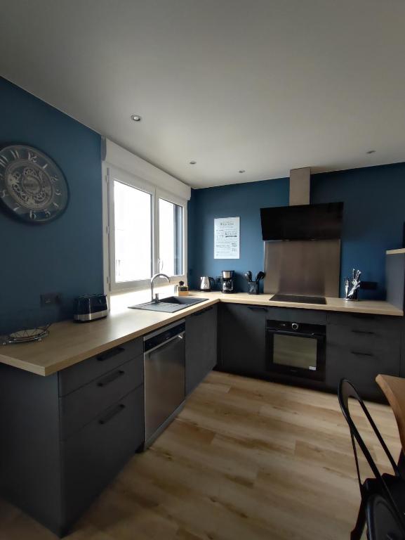 d&#39;une cuisine avec des murs bleus, un évier et une cuisinière. dans l&#39;établissement Le Gîte de Daisy, à Saint-Côme-du-Mont