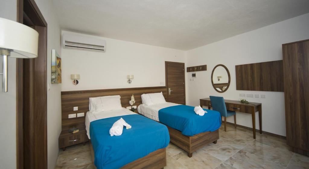 a hotel room with two beds and a desk at Slimiza Suites in Sliema