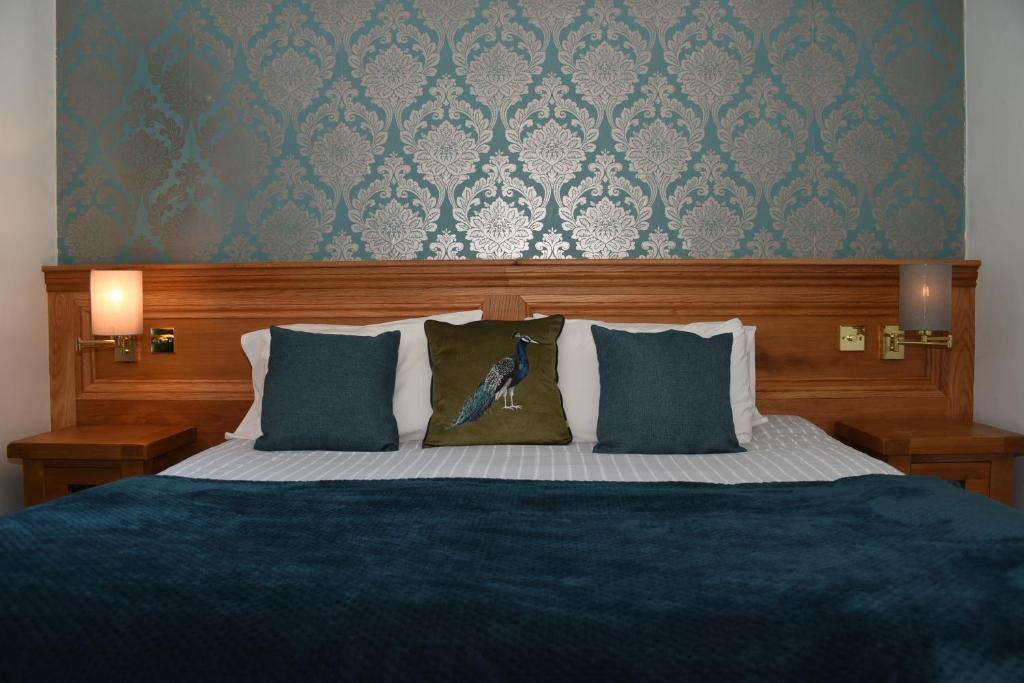 um quarto com uma cama grande com lençóis e almofadas azuis em Greyhound Hotel em Wales