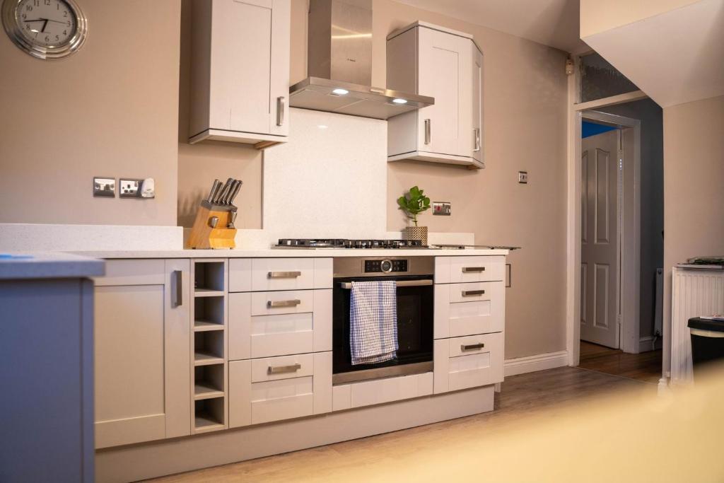 a kitchen with white cabinets and a stove at 3 BR House BHX HS2 Contractor Solihull FREE Parking in Sheldon