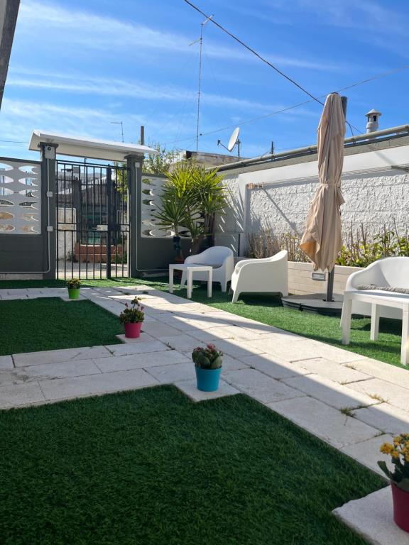 a patio with chairs and an umbrella on the grass at Truly Apulia in Bari