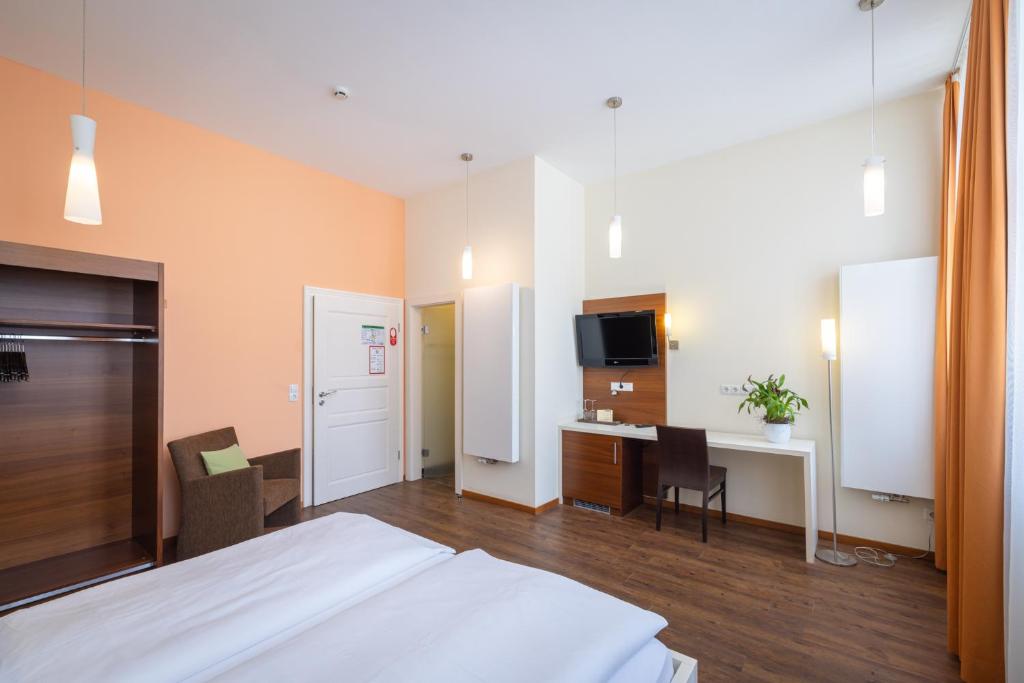 a hotel room with a bed and a desk and a tv at Altstadthof Freinsheim in Freinsheim