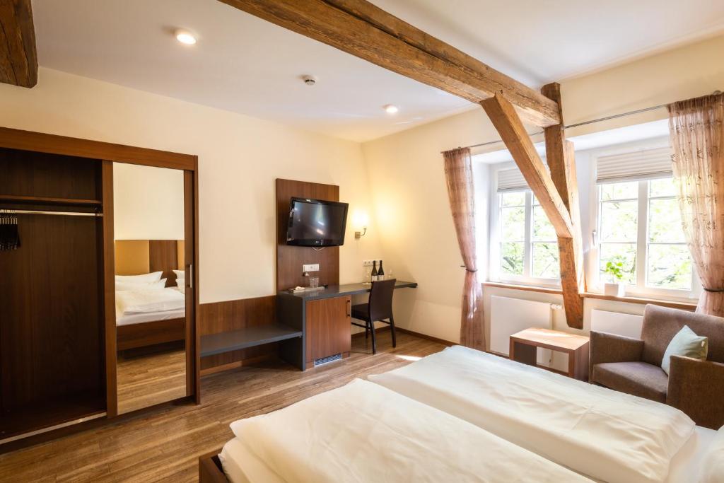 a hotel room with a bed and a desk and a television at Altstadthof Freinsheim in Freinsheim