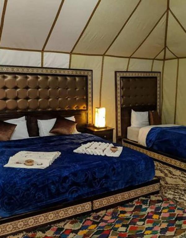 a bedroom with two beds in a tent at Merzouga Sahara Camp in Merzouga