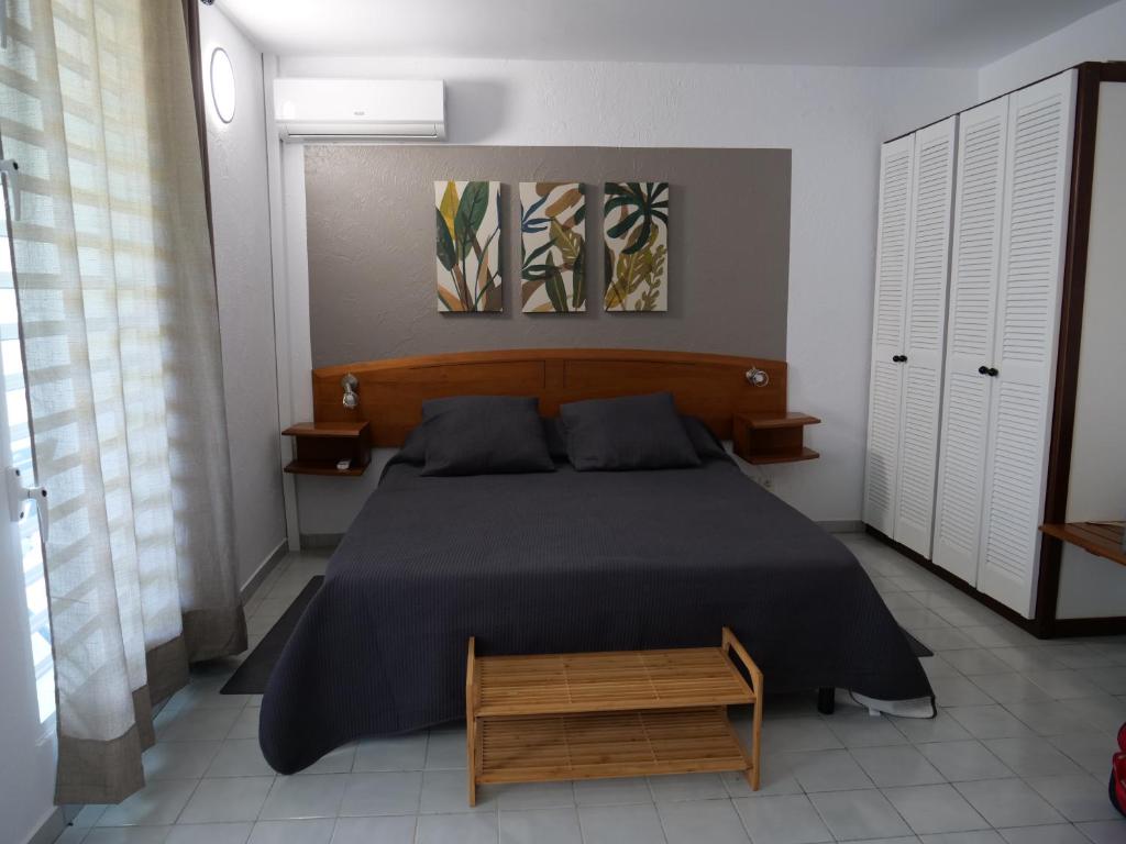a bedroom with a large bed with a wooden headboard at Village Kawann - Toumalacai 246 in Grand-Bourg