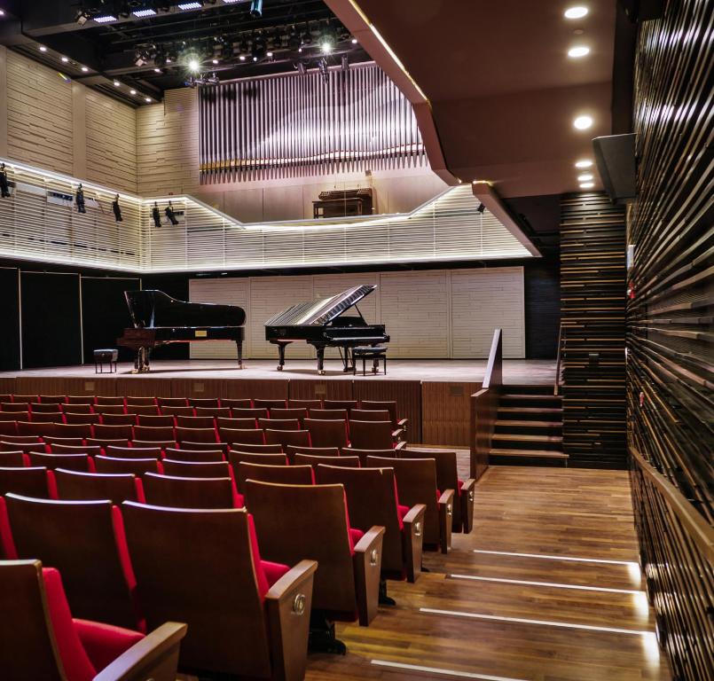 an empty auditorium with a grand piano and chairs at Elma Hotel and Art Complex in Zikhron Ya'akov