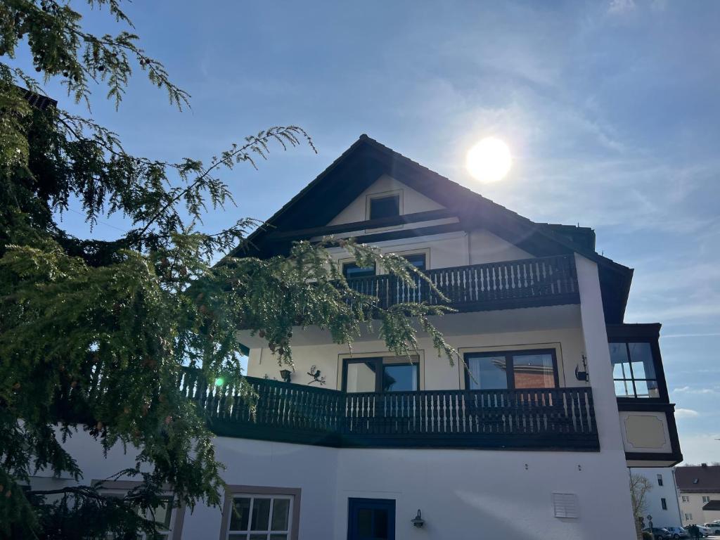 a white building with a balcony and the sun in the sky at Aparthotel Parsberg LFerstl in Parsberg