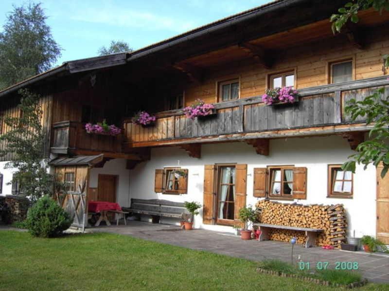 a house with a bench and a balcony with flowers at Ferienwohnung Regauer in Fischbachau