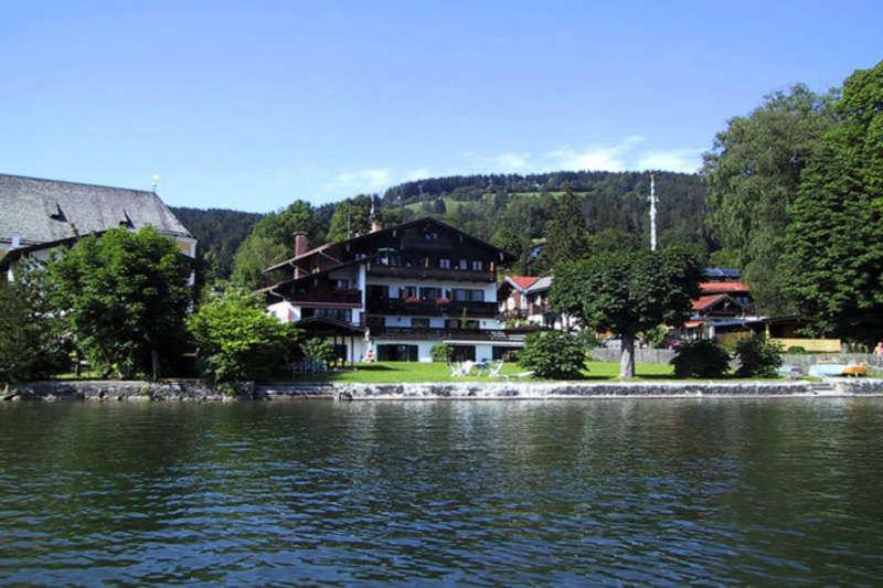 a large house sitting on the shore of a lake at Ferienwohnungen am See _ Hinterseer in Schliersee