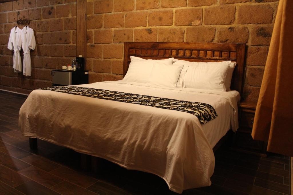 Cama en habitación con pared de ladrillo en Hotel Real Nirvana, en Tecozautla