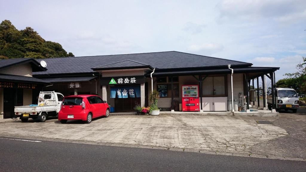 un edificio con un coche rojo estacionado frente a él en Maetakeso, en Yakushima