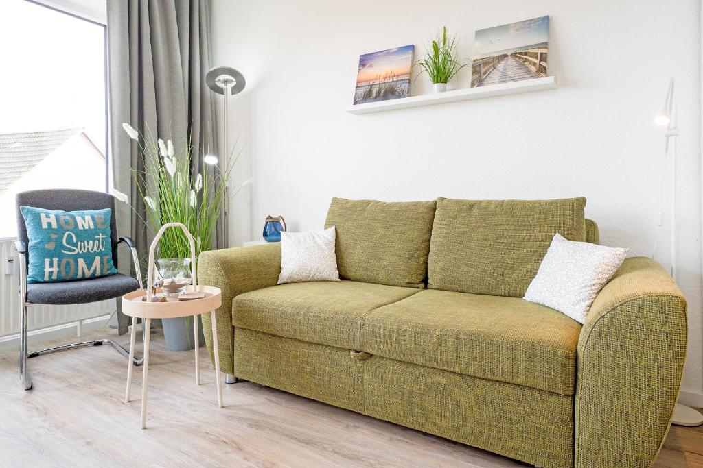 ein Wohnzimmer mit einer grünen Couch und einem Stuhl in der Unterkunft Haus Seebad Ausguck in Grömitz