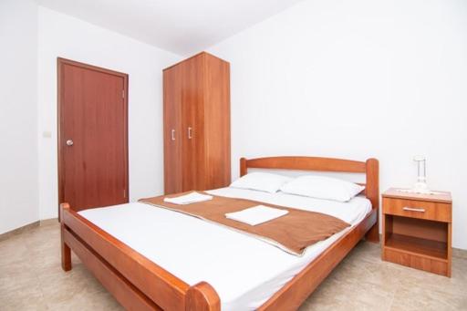 a bedroom with a bed with a wooden headboard and a night stand at Apartments Savić in Herceg-Novi
